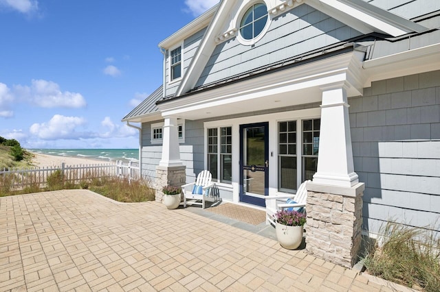 view of patio with a water view, fence, and a beach view