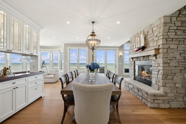 dining space featuring a stone fireplace, light wood-style flooring, and a healthy amount of sunlight