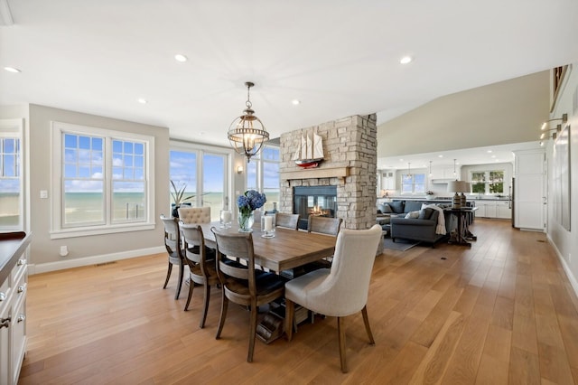 dining area with lofted ceiling, a fireplace, light wood-style flooring, and recessed lighting