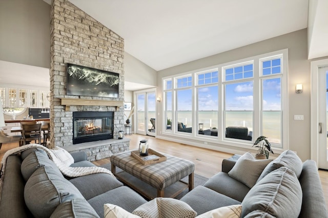 living room with high vaulted ceiling, a fireplace, and wood finished floors