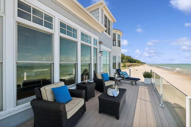wooden terrace featuring a water view and a view of the beach