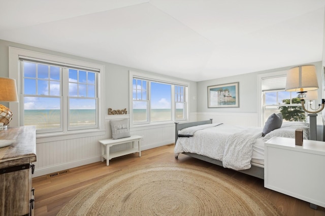 bedroom with visible vents, wood finished floors, and wainscoting