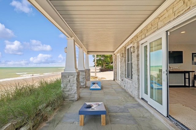 view of patio / terrace with a water view and a beach view