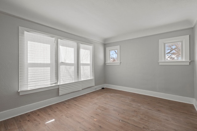 spare room featuring baseboards and wood finished floors