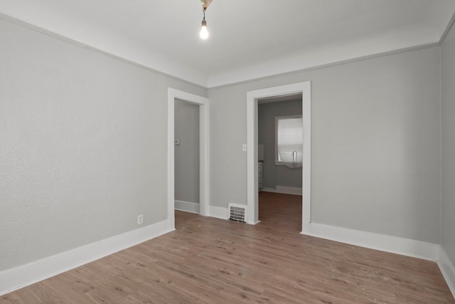 unfurnished room with baseboards, visible vents, and wood finished floors