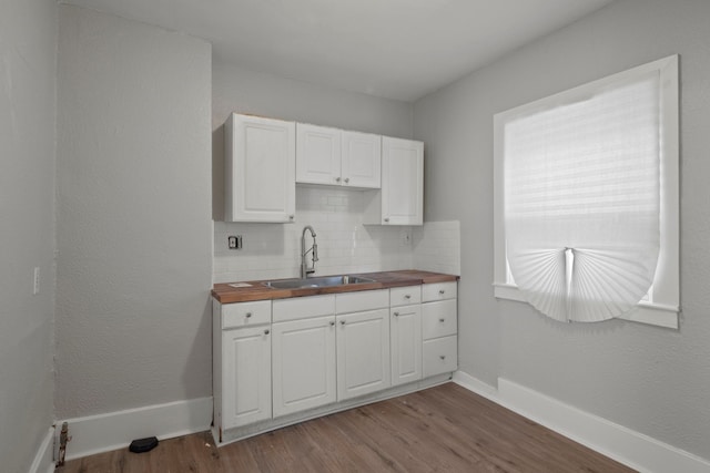 kitchen with butcher block counters, white cabinetry, dark wood finished floors, and a sink