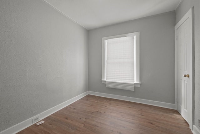 unfurnished room featuring a textured wall, baseboards, and wood finished floors