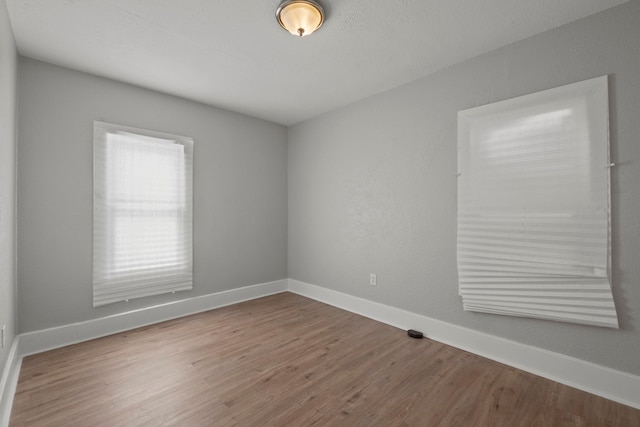 unfurnished room with baseboards and wood finished floors