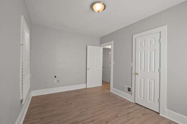 unfurnished bedroom featuring baseboards, visible vents, and wood finished floors