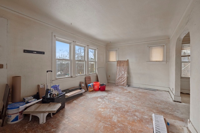 unfurnished room with arched walkways and a textured ceiling