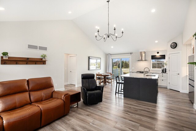 living room featuring visible vents, an inviting chandelier, wood finished floors, high vaulted ceiling, and baseboards