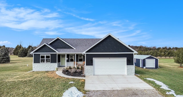 craftsman-style home with board and batten siding, stone siding, driveway, and a front lawn