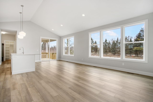 unfurnished living room featuring baseboards, visible vents, vaulted ceiling, light wood-type flooring, and recessed lighting