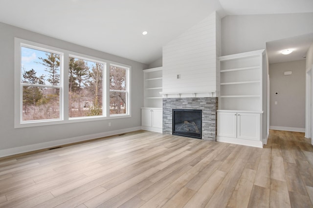 unfurnished living room featuring light wood finished floors, visible vents, baseboards, lofted ceiling, and a fireplace