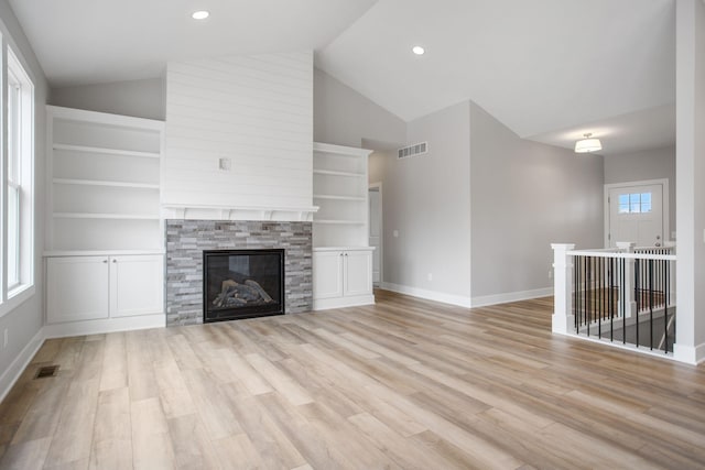 unfurnished living room featuring lofted ceiling, light wood-style flooring, a fireplace, and visible vents