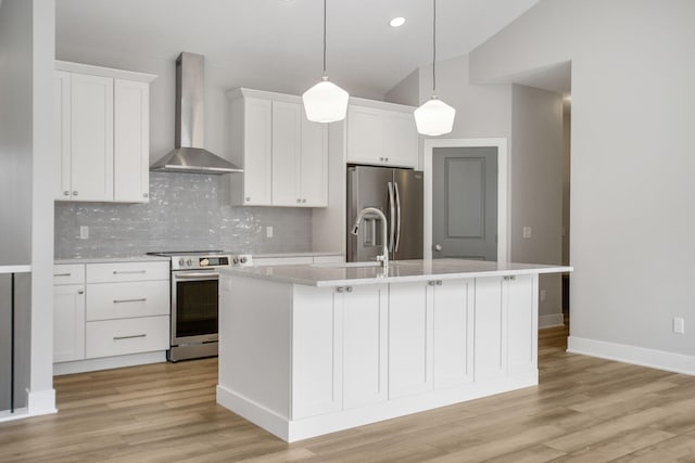 kitchen featuring a center island with sink, stainless steel appliances, white cabinetry, light wood-type flooring, and wall chimney exhaust hood