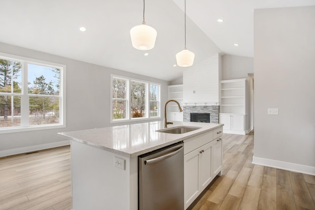 kitchen featuring a sink, white cabinets, stainless steel dishwasher, light wood-type flooring, and light stone countertops