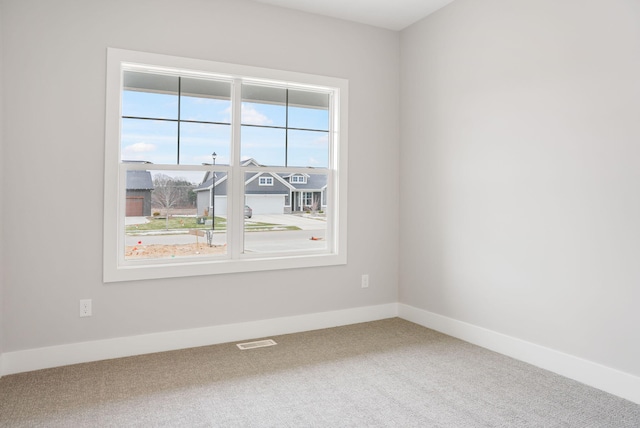 unfurnished room with carpet floors, baseboards, and visible vents