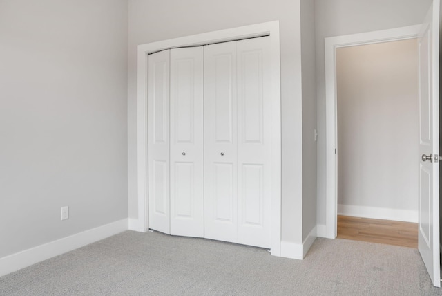 unfurnished bedroom featuring carpet floors, baseboards, and a closet