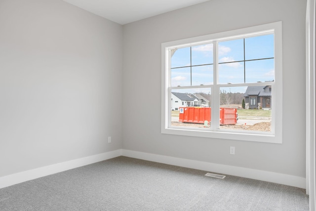 unfurnished room featuring carpet, visible vents, and baseboards