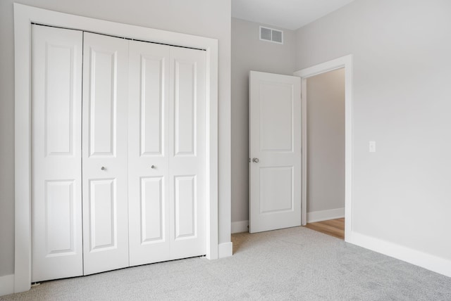 unfurnished bedroom featuring carpet floors, a closet, visible vents, and baseboards