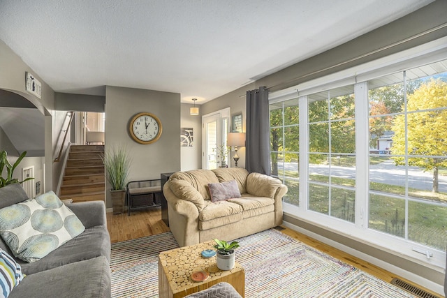 living room with baseboards, visible vents, wood finished floors, stairs, and a textured ceiling