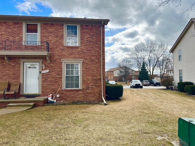 view of side of home with brick siding, a lawn, and dirt driveway