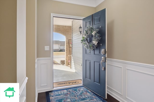 foyer entrance featuring a decorative wall and wainscoting