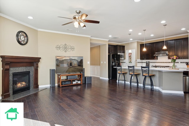 kitchen featuring under cabinet range hood, dark brown cabinetry, light countertops, and open floor plan