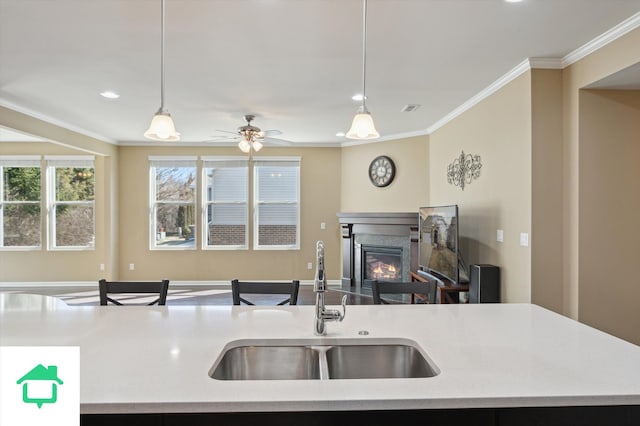 kitchen with open floor plan, crown molding, light countertops, and a sink