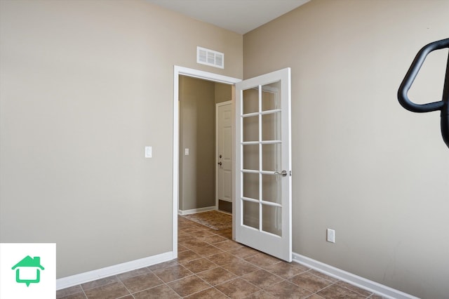 unfurnished room with visible vents, baseboards, and dark tile patterned floors