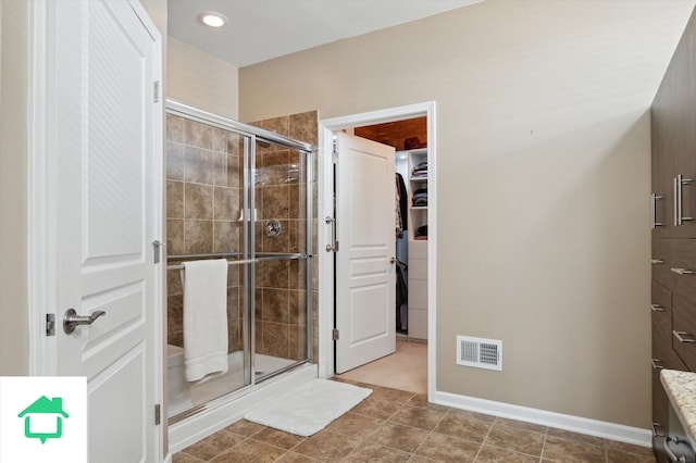 bathroom featuring a shower stall, a spacious closet, baseboards, and visible vents