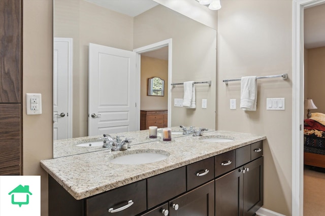 bathroom featuring a sink, double vanity, baseboards, and connected bathroom