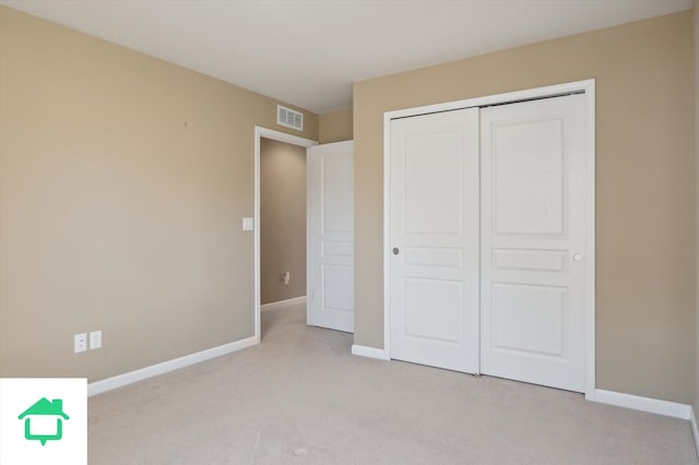 unfurnished bedroom with a closet, visible vents, light colored carpet, and baseboards