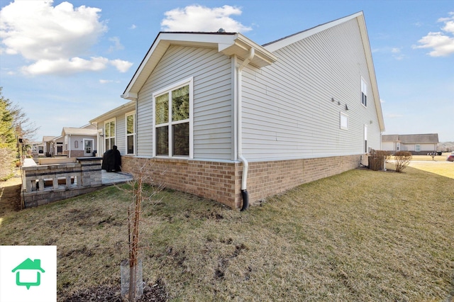 view of side of home with a patio, a yard, and brick siding