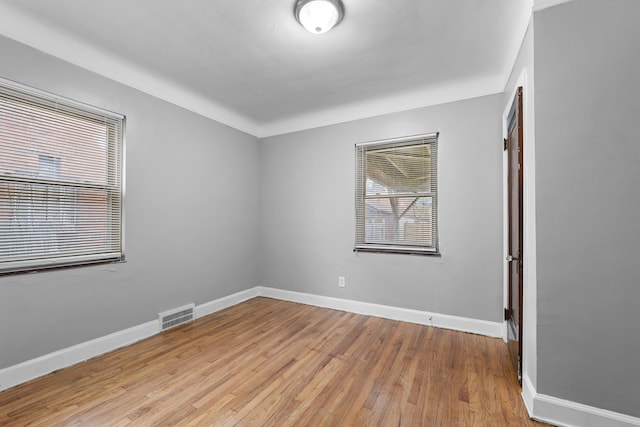 unfurnished room with visible vents, light wood-style flooring, and baseboards