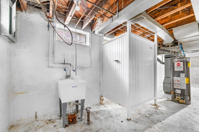 basement featuring gas water heater, visible vents, and concrete block wall