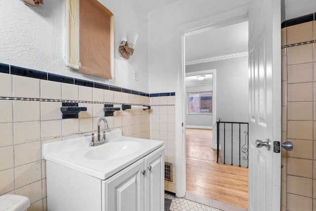 bathroom featuring tile walls, wainscoting, and vanity