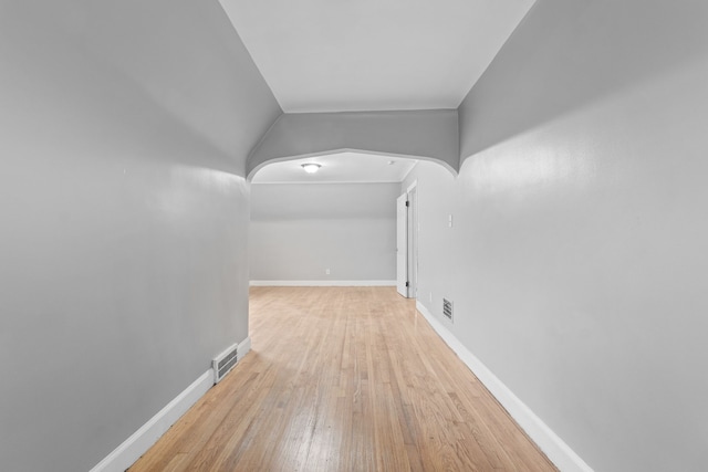 corridor featuring visible vents, baseboards, and hardwood / wood-style floors