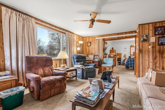 carpeted living area featuring ceiling fan and wood walls