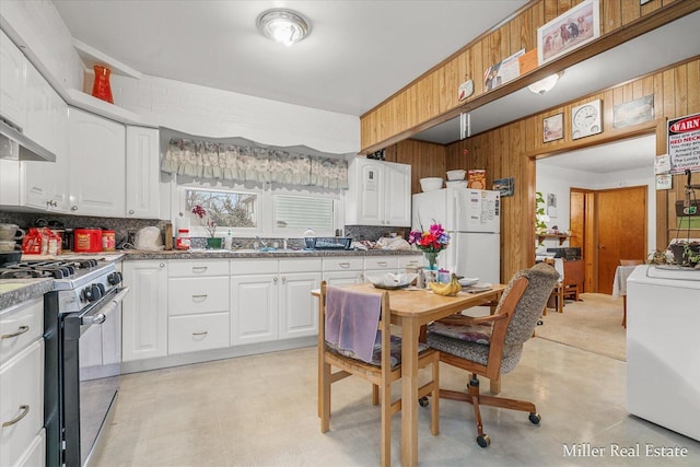 kitchen featuring freestanding refrigerator, tasteful backsplash, wood walls, and gas range