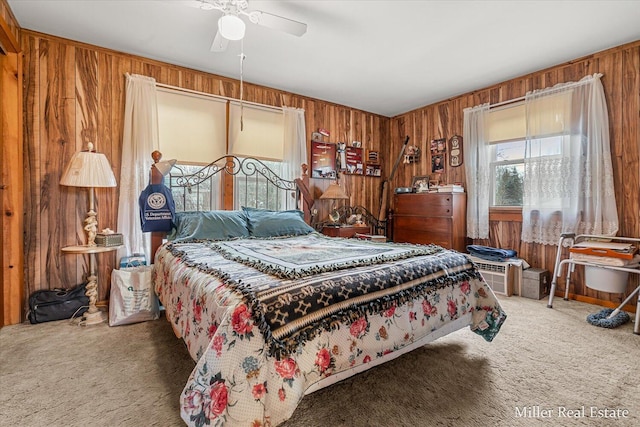 bedroom with carpet floors, wood walls, and a ceiling fan