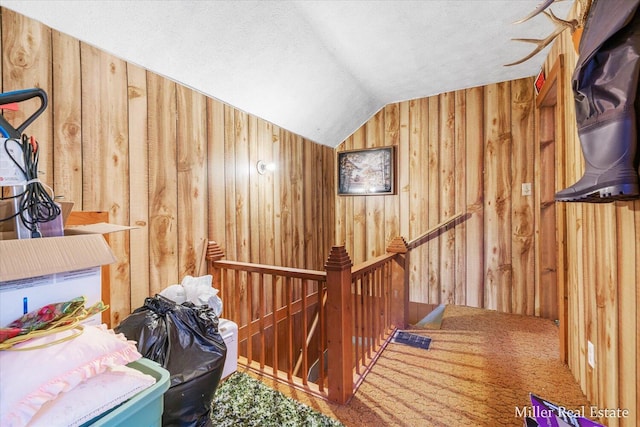 additional living space featuring vaulted ceiling, wooden walls, and a textured ceiling