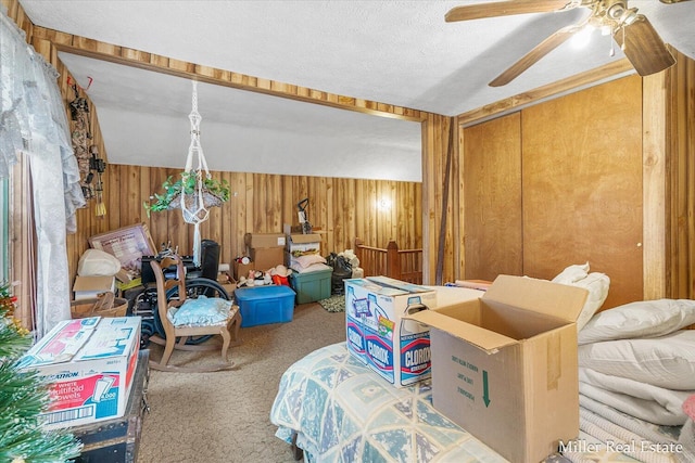 interior space featuring a textured ceiling, a ceiling fan, and wooden walls