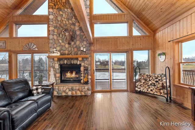 living room featuring a stone fireplace and wood walls