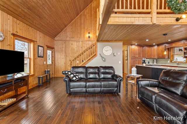 living room featuring high vaulted ceiling, wooden walls, dark wood-style flooring, wood ceiling, and stairs