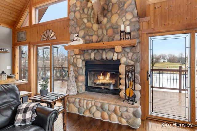 living area with wood-type flooring, a stone fireplace, high vaulted ceiling, wooden ceiling, and beamed ceiling