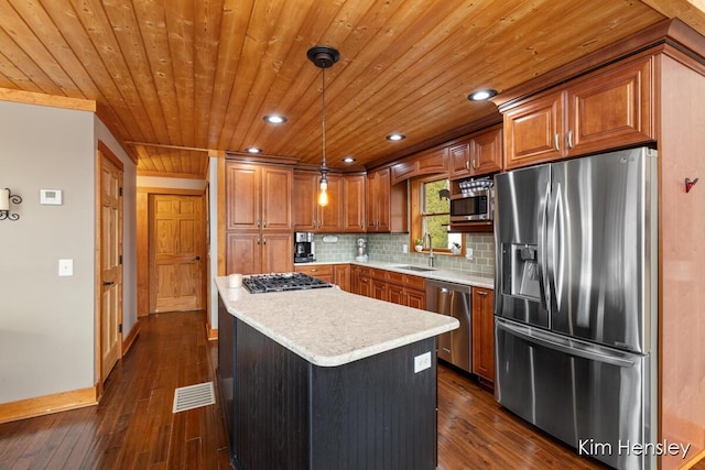 kitchen featuring appliances with stainless steel finishes, brown cabinets, a sink, and backsplash