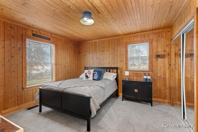 bedroom with light carpet, wooden ceiling, multiple windows, and baseboards