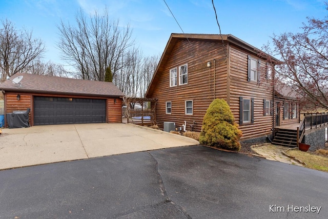 view of side of home with a garage, a deck, cooling unit, and an outbuilding